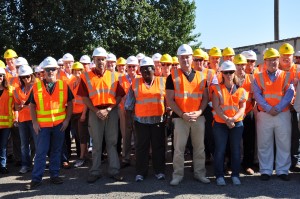 Group of people at a facility tour wearing hard hats and reflective vests
