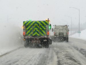 Back view of a plow with reflective markings and lights on a snowy road